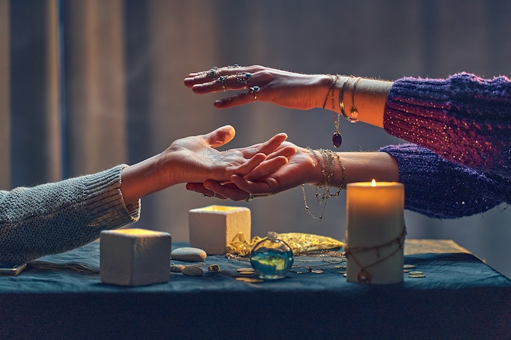 Foto hexenfrau, die über handfläche während des okkulten spirituellen ritus und des wahrsagungsrituals um kerzen und andere magische accessoires buchstabiert. magische illustration