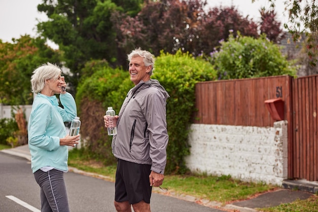 Hicimos nuestro ejercicio para el día Captura recortada de una alegre pareja de ancianos bebiendo agua después de correr juntos afuera en un suburbio