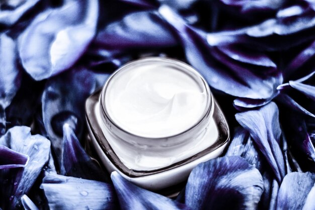 Foto hidratante de crema facial de lujo para la piel facial sobre fondo de flores azules cosméticos de spa floral essense y emulsión de belleza para productos de marca para el cuidado de la piel