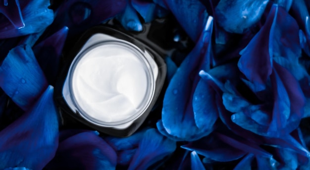 Hidratante de creme de rosto de luxo para pele facial em fundo de flor azul, cosméticos de spa floral essense e emulsão de beleza para produtos de marca de cuidados com a pele