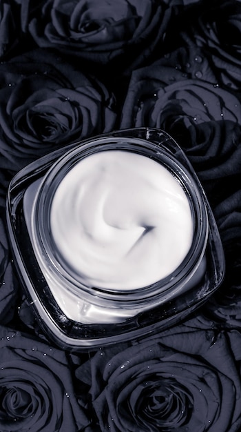 Hidratante de pele creme facial e rosas negras flores produto cosmético de luxo para cuidados com a pele em fundo floral como design flatlay de férias de marca de beleza