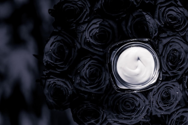 Foto hidratante de pele creme facial e rosas negras flores produto cosmético de luxo para cuidados com a pele em fundo floral como design flatlay de férias de marca de beleza