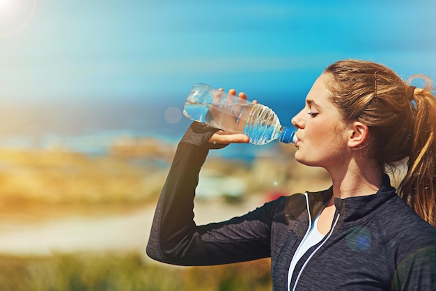 Hidrátese para un gran entrenamiento Foto de una joven deportista bebiendo agua al aire libre