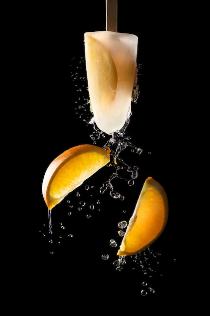 Hielo de frutas con salpicaduras de agua y trozos de naranja voladora