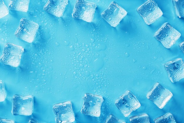 Hielo hecho de cubos alineados con gotas sobre un fondo azul con espacio libre