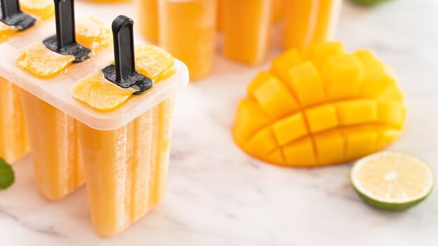 Hielo de paleta de fruta de mango fresco en la caja de moldeado de plástico en la mesa de mármol brillante