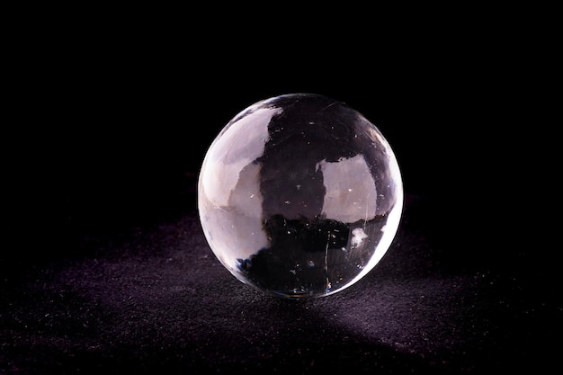 Hielo translúcido cristalino y esfera de cristal aislado sobre fondo negro en alfombra de gamuza