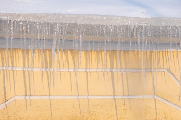 Foto los hielos que cuelgan del techo de la casa la nieve que se derrite en el techo los peligrosos hielos transparentes y afilados que cuelgen en el tejado la seguridad