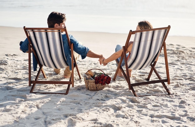 Hier für die Meereswellen und faulen Tage Rückansicht eines Paares mittleren Alters, das in seinen Liegestühlen am Strand sitzt