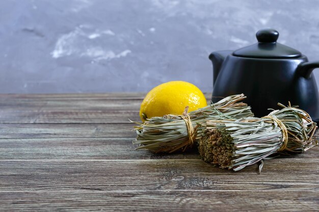 Hierba de limón seca orgánica (Cymbopogon flexuosus) en racimos y fruta de limón sobre una mesa de madera. Hierbas para el té.