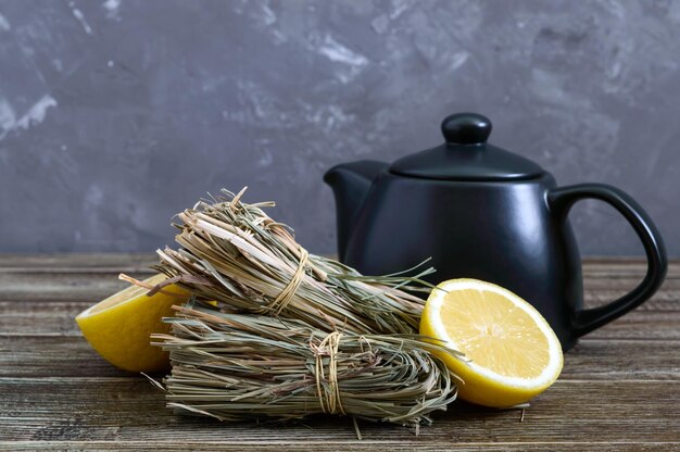 Hierba de limón seca orgánica (Cymbopogon flexuosus) en racimos y fruta de limón sobre una mesa de madera. Hierbas para el té.