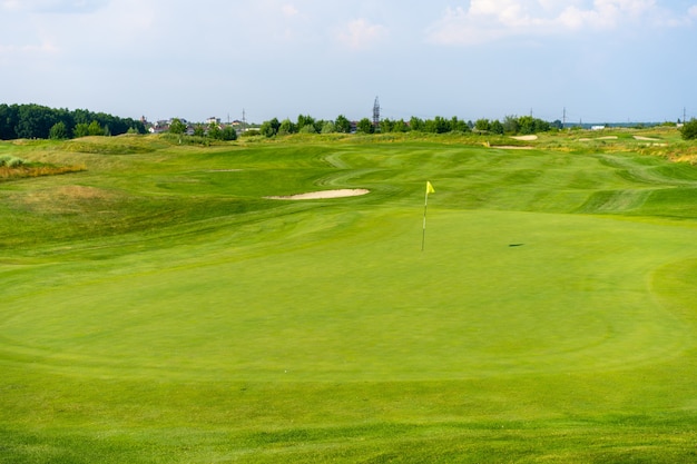 Hierba verde y bosques en un campo de golf con trampa de arena