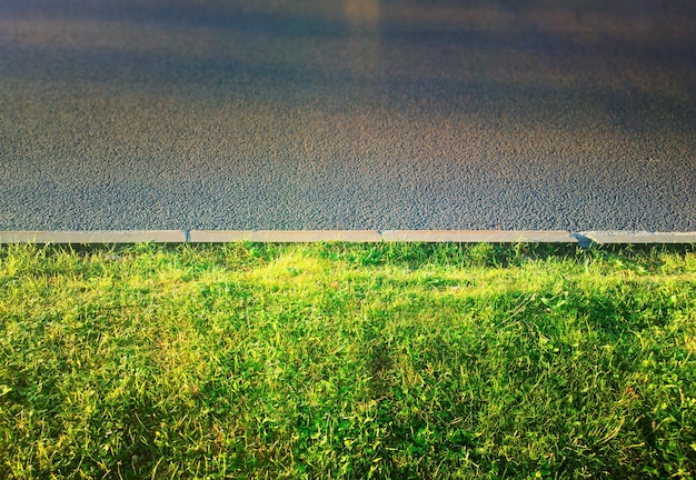 Hierba verde en el fondo de la ciudad de acera de carretera