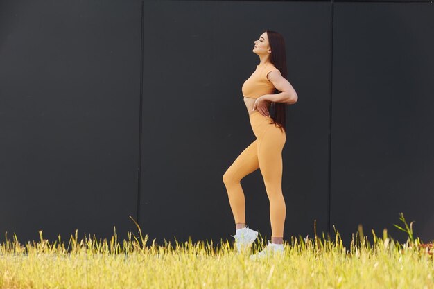 Hierba verde Mujer joven en ropa deportiva tiene sesión de fitness al aire libre
