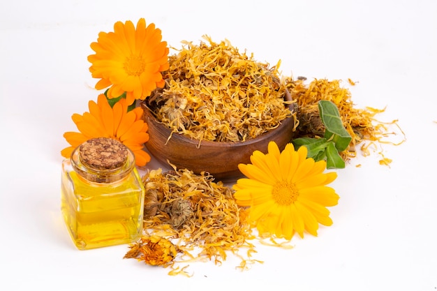 Hierbas calendula officinalis en el vaso y gota de aceite aislado