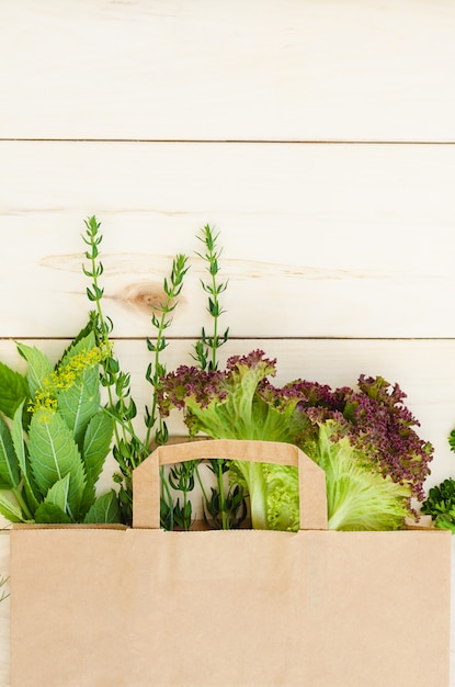 Hierbas frescas en bolsa de papel ecológico sobre mesa de madera. entrega de comida.