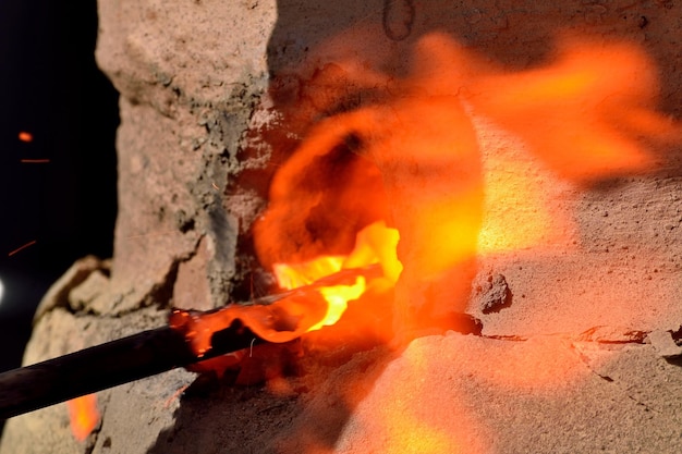 Hierro fundido saliendo de la boca de un horno de fundición artesanal.