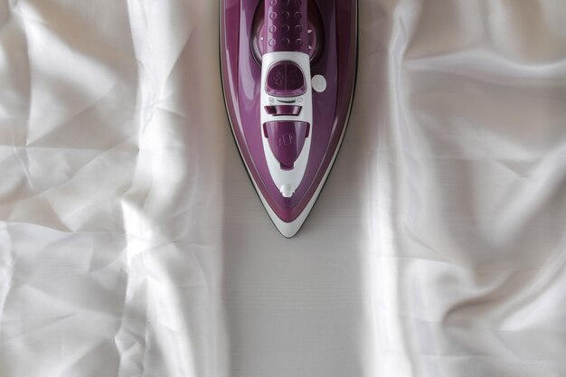 Hierro lila sobre un trozo de tela blanca arrugada electrodomésticos.