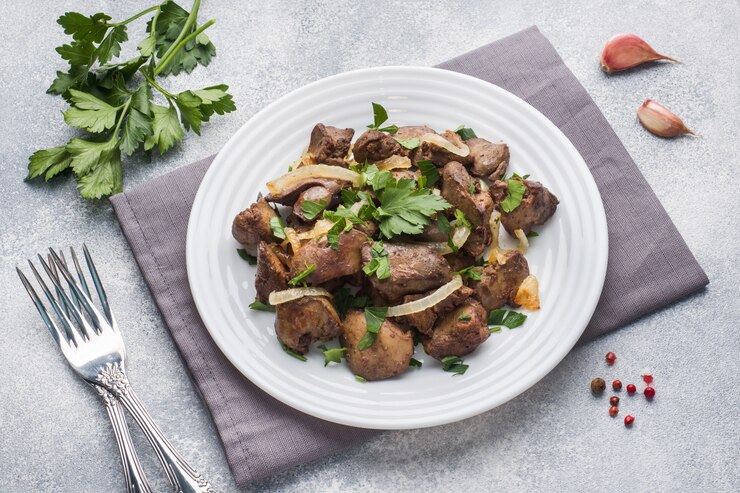 Hígado de pollo al horno con cebolla en un plato.