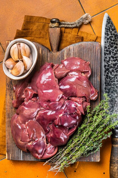 Hígado de pollo crudo menudencias de aves frescas sobre tabla de madera Fondo naranja Vista superior