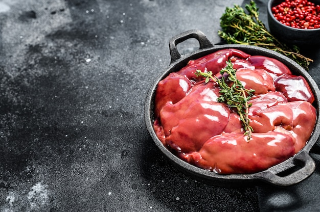 Hígado de pollo crudo en una sartén en negro. Vista superior. Copia espacio