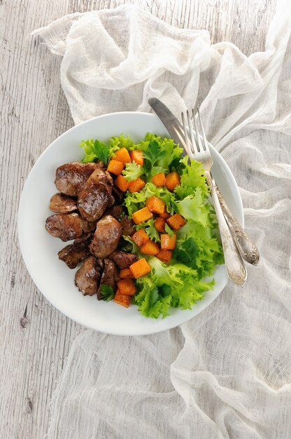 Hígado de pollo frito con guarnición de verduras, calabaza al horno en hojas de lechuga