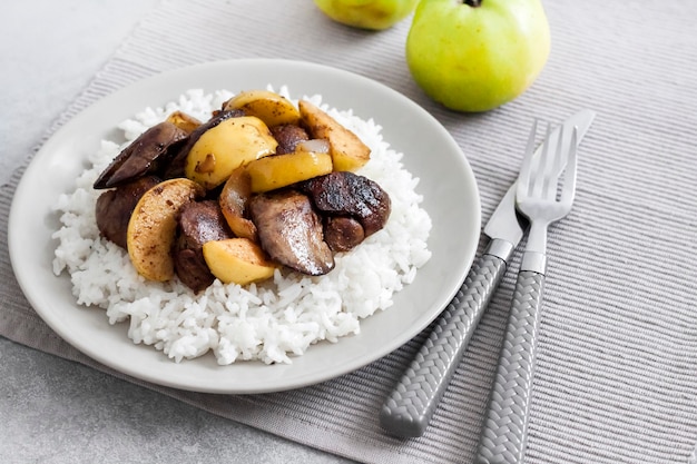 Hígado de pollo frito con manzanas servido con arroz blanco en un plato