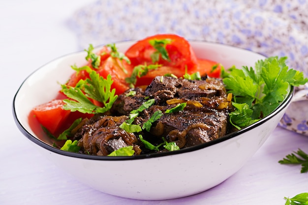 Hígado de res asado o a la parrilla con cebolla y ensalada de tomates, cocina del Medio Oriente.