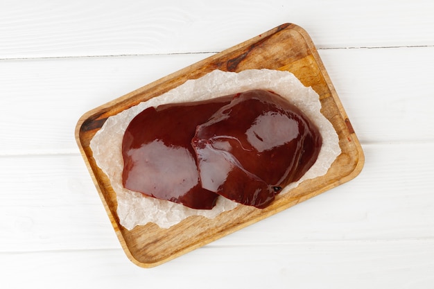 Foto hígado de res cruda sobre tabla de madera en la mesa