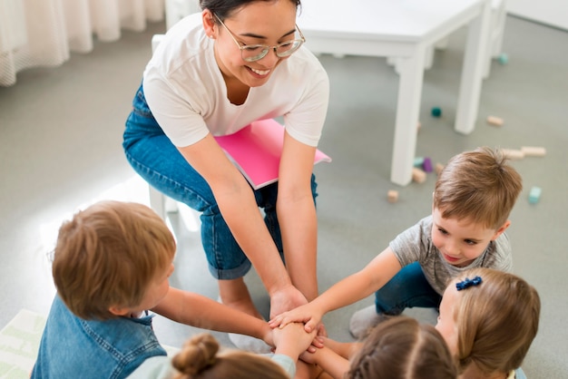 Foto high angle lehrerin spielt mit ihren schülern im kindergarten