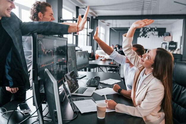 High Five geben Das Team von Börsenmaklern arbeitet in einem modernen Büro mit vielen Bildschirmen