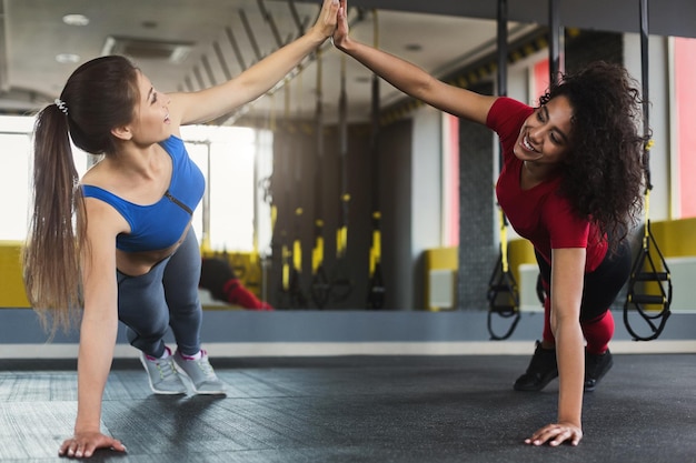 High Five im Fitnessstudio, Fitnessmädchen, die während des Trainings Liegestütze machen