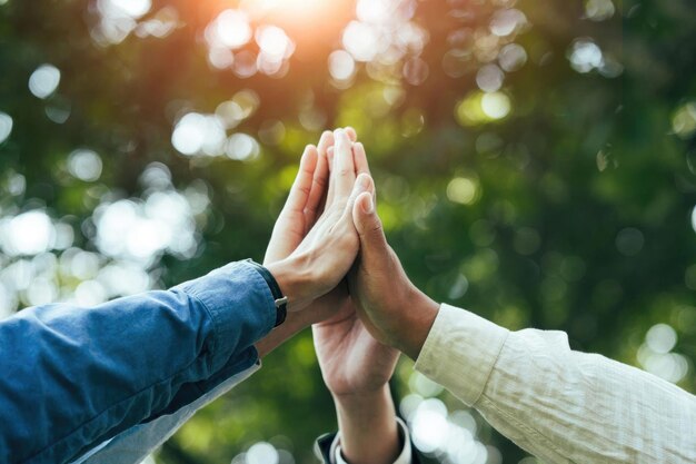 High-Five-Teamwork ist ein Team-Zusammen-Einheits-Konzept. Schutz der Natur, der Umwelt, Gruppen von Menschen verschiedener Nationalitäten, Geschäftsteam-Erfolgskonzept gemeinsam