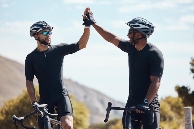 High five vencedor e equipe de ciclismo de ciclistas se divertindo andando juntos ao ar livre na natureza Felizes ciclistas masculinos excitados e em forma em uma pausa após o exercício e treinamento no meio ambiente