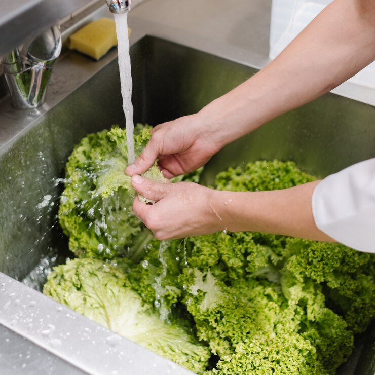 Higiene alimentar em um restaurante. Cozinhe a salada verde na pia da cozinha antes de adicioná-la à refeição.