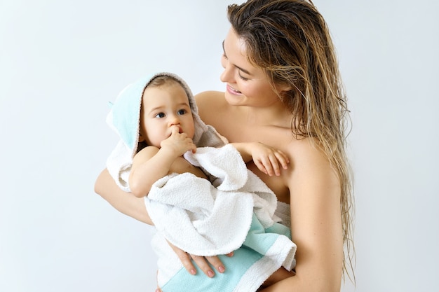 Higiene y cuidado del bebé. Madre joven y feliz y su lindo hijo después de bañarse.