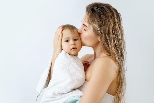 Higiene y cuidado del bebé. Madre joven y feliz y su lindo hijo después de bañarse.