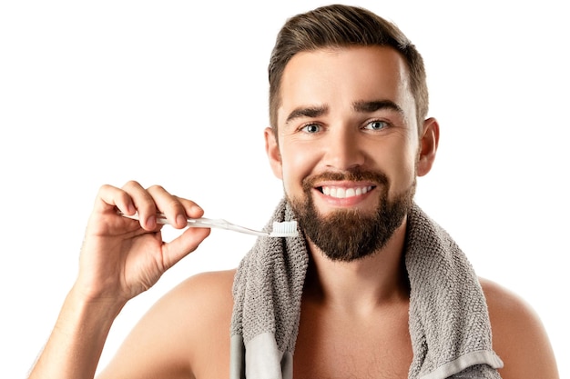 Higiene y cuidado de los dientes - Hombre guapo con hermosa sonrisa sosteniendo cepillo de dientes sobre fondo blanco.