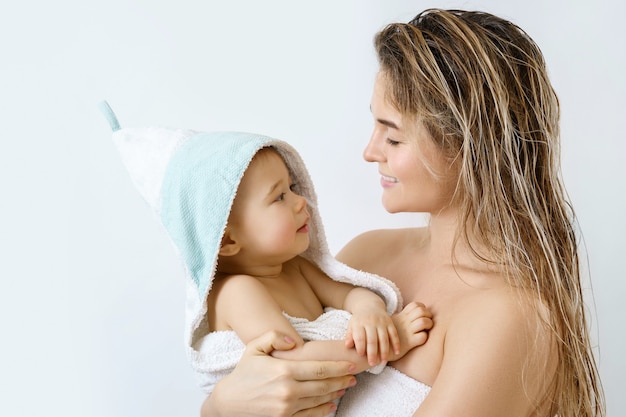 Higiene e cuidados com o bebê. Jovem e feliz mãe e seu lindo filho após o banho.