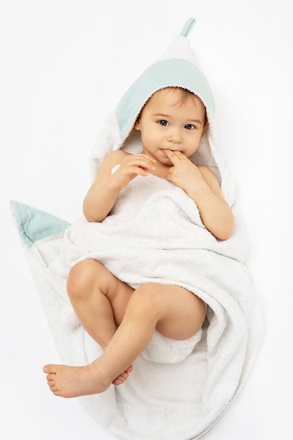 Higiene e cuidados com o bebê. Lindo menino infantil enrolado em uma toalha com capuz depois do banho.