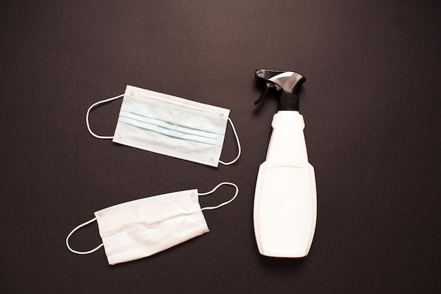 Higiene e limpeza: máscaras protetoras médicas, frasco de anti-séptico e sabonete líquido sobre fundo preto close-up. Vista do topo.