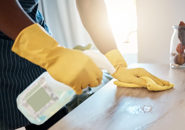 Higiene de manos y detergente para limpiar la mesa doméstica o sanitaria para eliminar bacterias o suciedad en el hogar Mano del trabajador de la salud que limpia el escritorio con una botella de spray químico y un paño para protegerse de los gérmenes