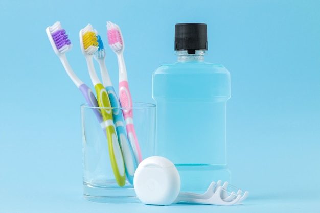 Foto higiene oral. escova de dentes, fio dental e enxágue para boca e dentes em um azul suave