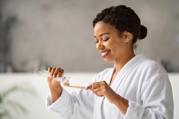 Higiene oral linda mulher negra aplicando pasta de dente na escova de dentes de bambu ecológico