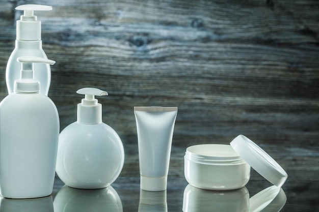 Higiene-Produkte, weiße Kunststoff-Pumpspender, Tube und Glascreme auf Vintage-Holzhintergrund
