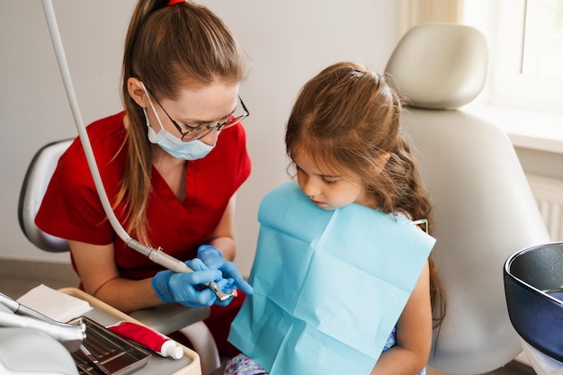 Higiene profesional para los dientes del niño en odontología Limpieza dental profesional para niña El dentista pediátrico examina y consulta al paciente niño en odontología