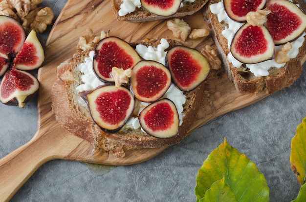 Higos cortados por la mitad sobre pan tostado con queso y nueces Copiar espacio