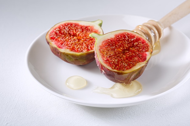 Higos cortados en trozos y rociados con miel en un plato blanco. vitamina comida sana orgánica