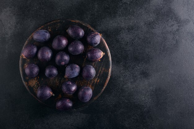 Higos frescos en un recipiente sobre una madera oscura, vista superior con espacio de copia