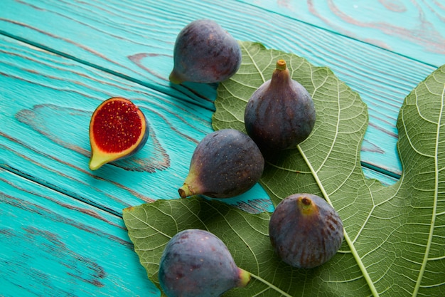Foto higos, frutas crudas cortadas y hojas de higuera en azul